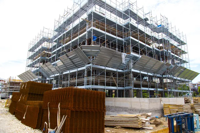Edificio B — struttura in elevazione, ponteggi e materiali a piè d'opera (giugno 2026)